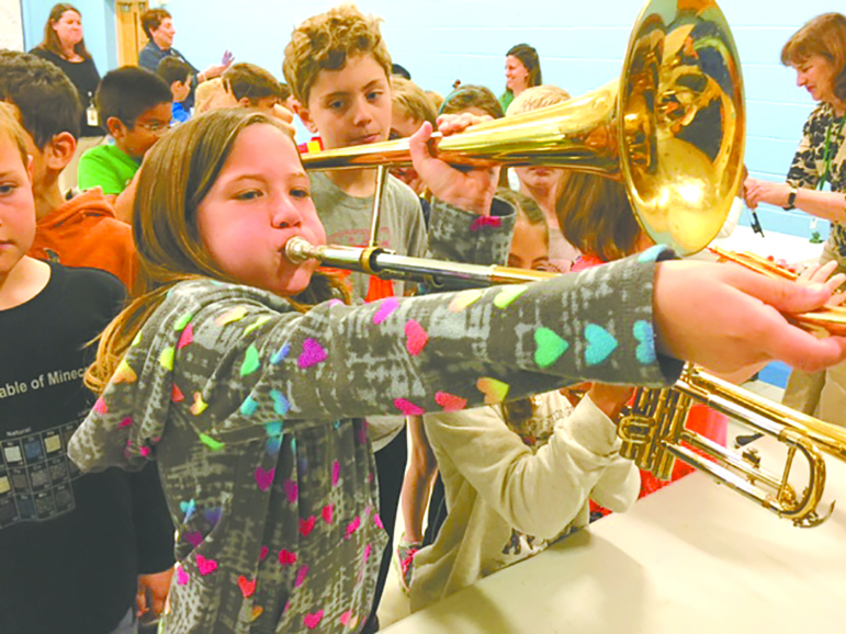 Second grader Samantha Markowski tries a trombone the Hartford Symphony brought with their Instrument Zoo to Spaulding School.