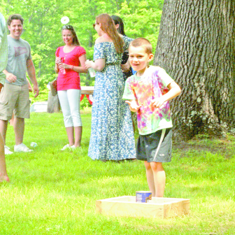 Young Tristan Bermani, 6, provides body English for his throw in a “washer toss in a coffee can” version of the cornhole game during this year’s memorial picnic for Cpl. Stephen R. Bixler.