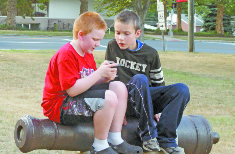 Noah Greico of Suffield and his friend Brenin Forbes of Windor Locks, both 10, share an iPhone playing Pokémon Go on the Suffield Green on July 22. The cannon they’re sitting on is a Pokémon gym, where the game’s monsters can compete.