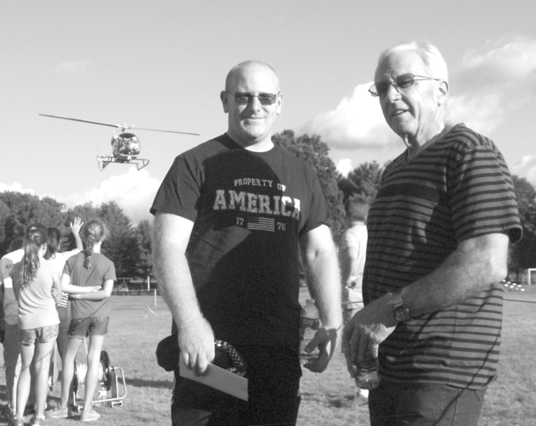 New Deputy Chief Richard Brown, left, and new Superintendent of Police Services Anthony Riello are pictured at the National Night Out, a community-building event originated here by Riello last year. Landing in the background is the helicopter that had been engaged to provide short sightseeing rides during the August 2 event.