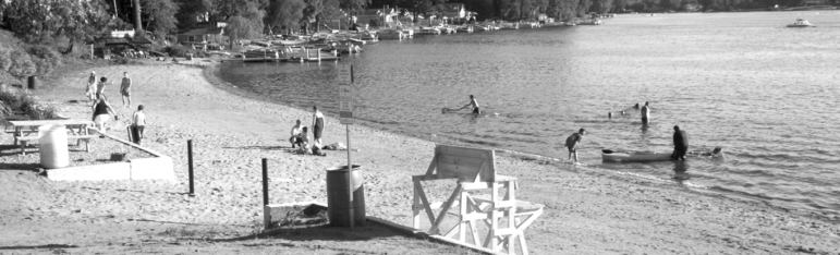 Beachgoers enjoy the water and the sand on a quiet, very warm Sunday afternoon in mid-July. The Town beach extends down to where the docks fill the shoreline along Middle Pond at Lake Congamond.