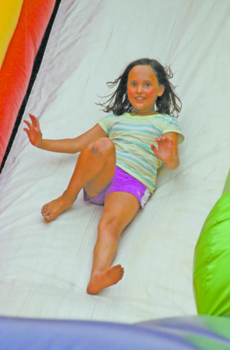 Mya Johnson, 7, reaches the end of the slide on one of the bounce houses.