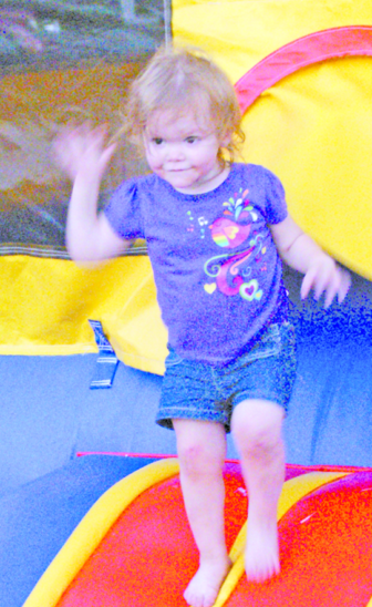 Kylie Lemine, 2, glows with a doll-like smile as she steps out of a bounce house doorway.