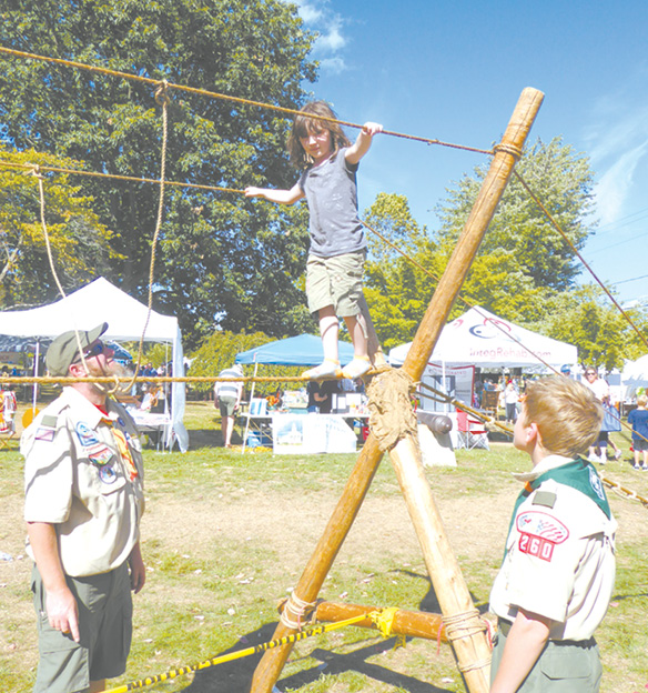 Rayne Daigle, 6, very carefully ventures out on Boy Scout Troop 260’s rope bridge. Scout leader Mike Cremins and Scout Jacob Quinn assure her safety for the crossing.