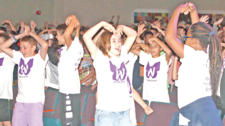 Enthusiastically dancing along with the speaker, Suffield Middle School students participate in an unusual early-morning assembly program called “Wingman.”