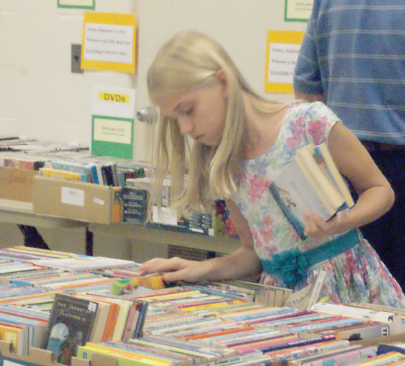 Young Claudia Skoczylas, 9, searches intently for another book to add to her selections. She was one of many customers who came to the Library Friends’ sale on Sunday, October 11, when prices were cut in half.