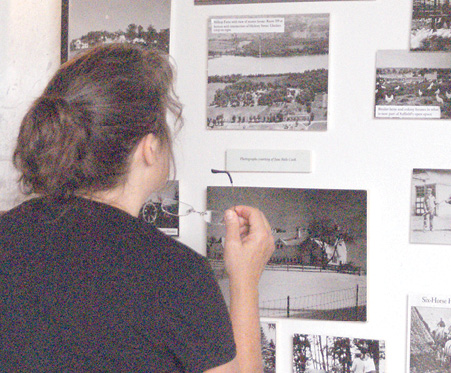 Diane Caswell Christian, who grew up across Mapleton Avenue from Hilltop Farm, studies an aerial view of her childhood neighborhood, exhibited among many old photos of the area.