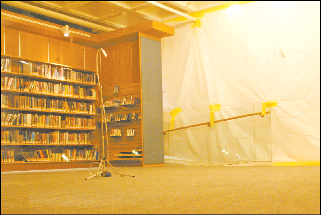 A collector stands in the north end of the upper level of Kent Memorial Library, one of the several regions of the building that were partially isolated with plastic sheeting for the new air tests that started on November 14. The intent is to determine the source of airborne PCB contamination revealed last spring. (This photo was taken in the evening, through the western north window.)