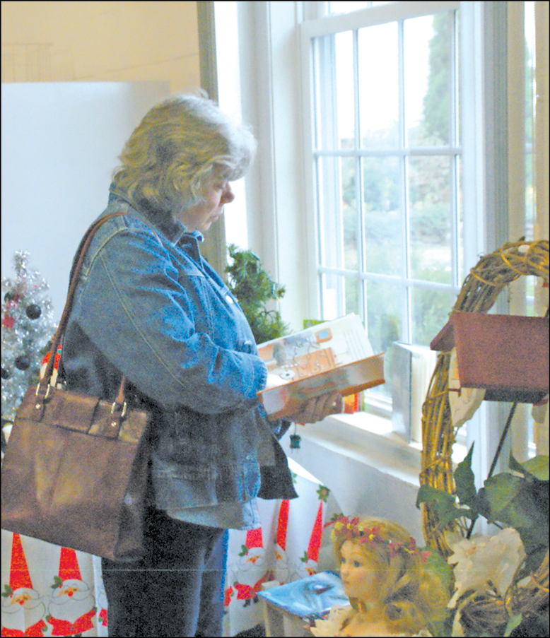Among the sale tables in Fellowship Hall at West Suffield Congregational Church, Virginia Pacquette moves to a window to examine a child’s book she might purchase.