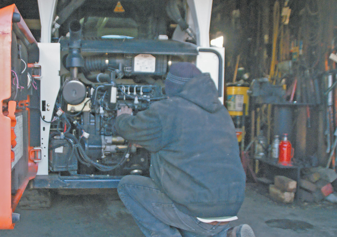 Grumbling about diesel on a cold winter afternoon in his equipment shed, an unidentified Suffield farmer changes the fuel filter on his Bobcat.