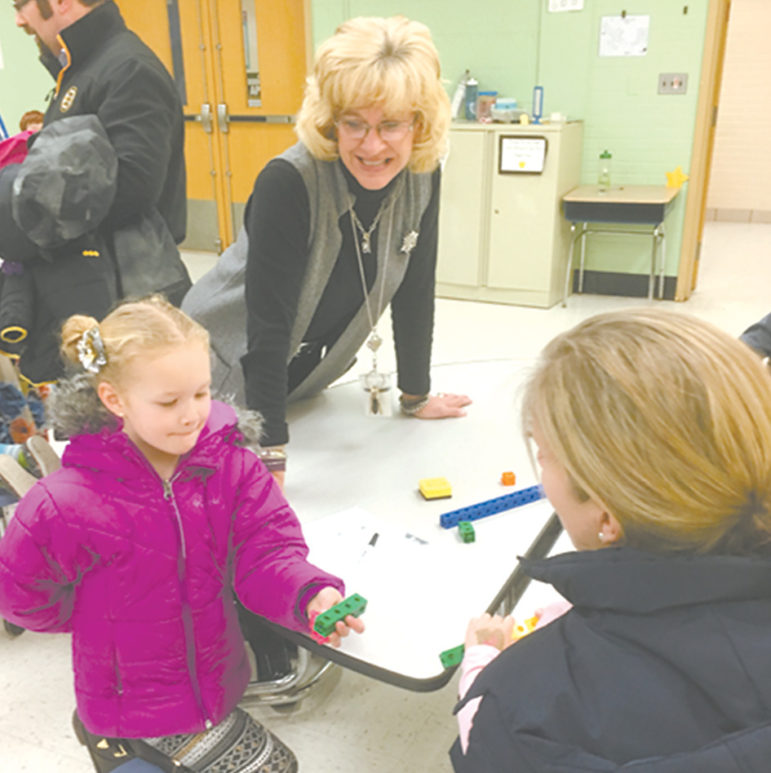Grade 1 teacher Suzanne Wosko observes her first grade student Peyton Benito engage with her mother in a conversation about math.