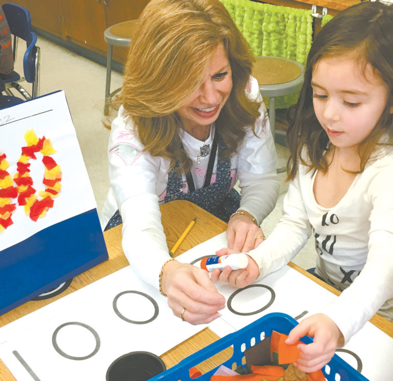 Spaulding School teacher Penny D'Aleo assists kindergarten student Ella Boys with an activity to celebrate the 100th Day of School.
