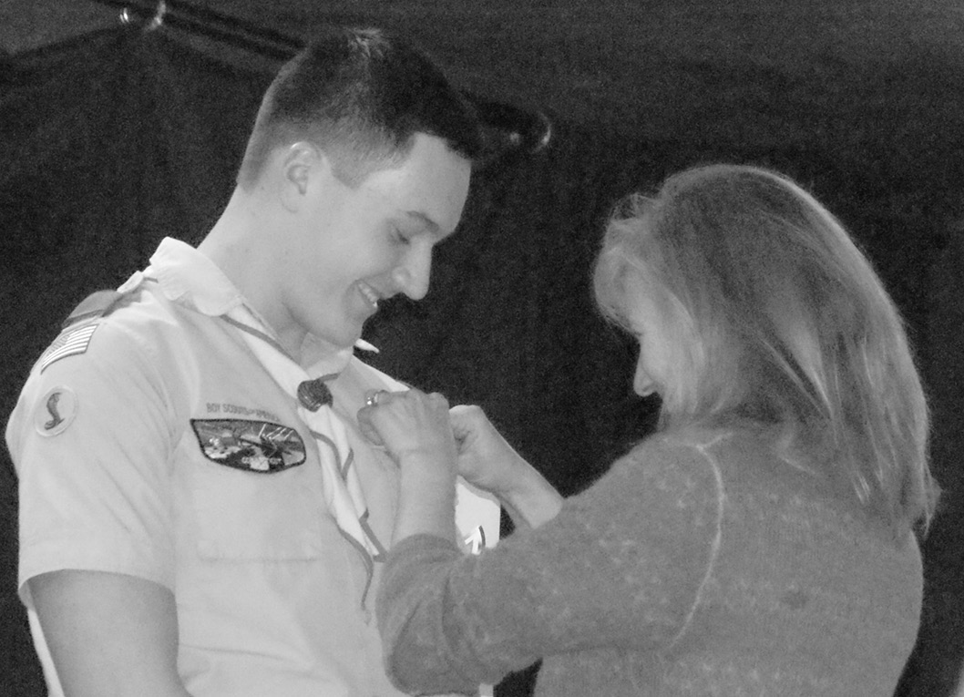 Stone Nadeau smiles proudly as his mother, Linda, pins his new Eagle Scout badge, presented in Boy Scout Troop 260's traditional Eagle ceremony at Second Baptist Church on February 14. For his Eagle Service Project, Stone led volunteers installing a new roof on the pavilion at the Jesse Fowler Smith Forest on Halladay Avenue W.