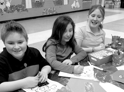 Three happy students prepare very cool valentines in an after school Parks & Rec program at McAlister Intermediate School on Valentine's Day. From the left: Gavin Griggs, Keila Silva and Emily Griggs.