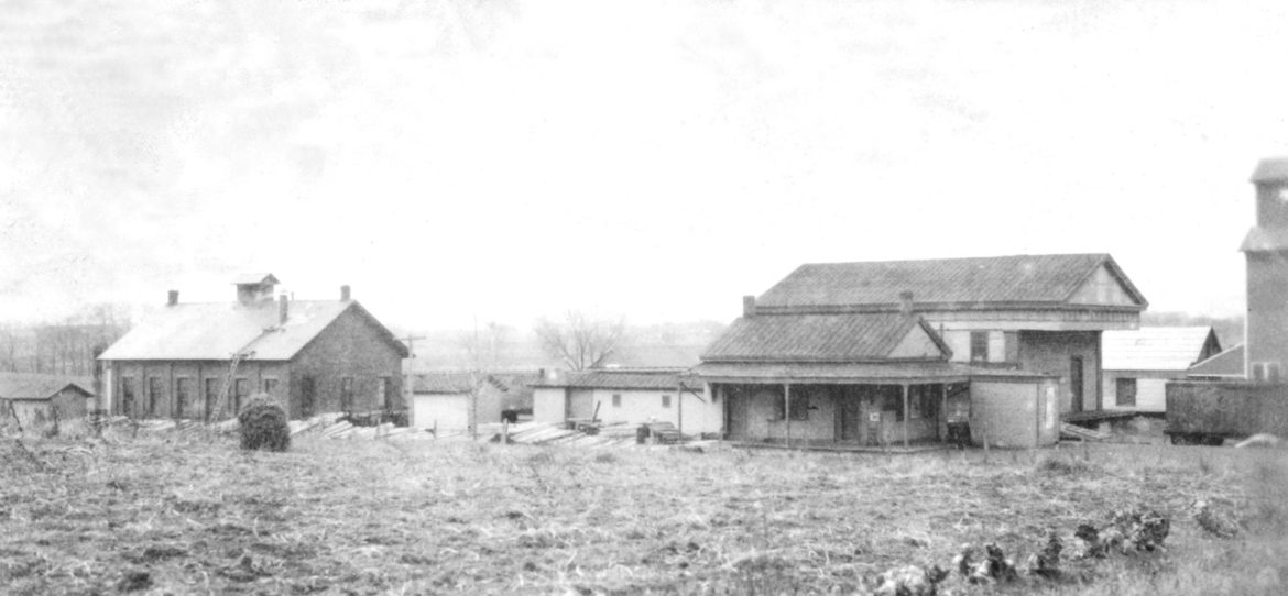 This unfamiliar scene was pictured on November 24, 1922, and the photo was taken looking southwest from Depot Street (now Mountain Road) from a spot in front of today’s Three Figs. The only building still there now is the tall one at the right edge: the Sikes grist mill. With its elevator top removed, it’s now the Nath Building at the corner of Ffyler Place. The big building with the overhanging column-less portico is the railroad freight house, which was repurposed in about 1869 from its previous role as the Congregational Church on High Street. The other two buildings are the depot and the engine house.