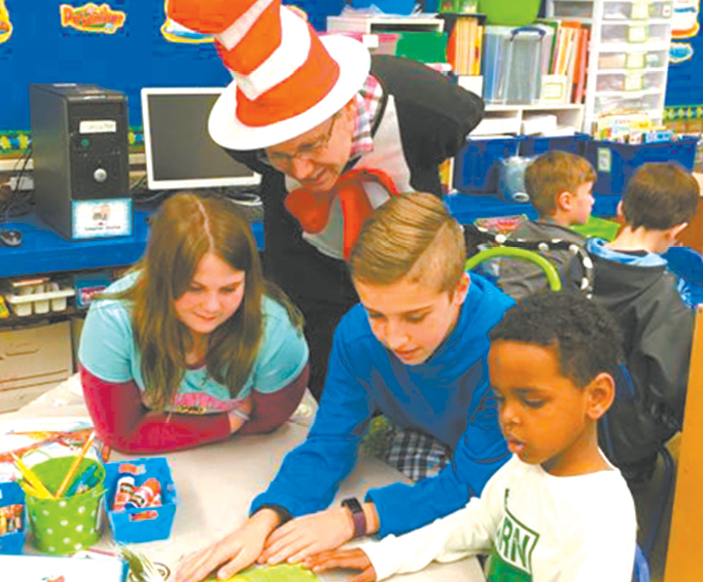 McAlister students Madelyn Eckley and Joshua Zenczak read to Spaulding kindergartener Tay Campagnola in Mrs. Reinhard’s kindergarten classroom, while The Cat in the Hat, aka Mr. Dunn, looks on.