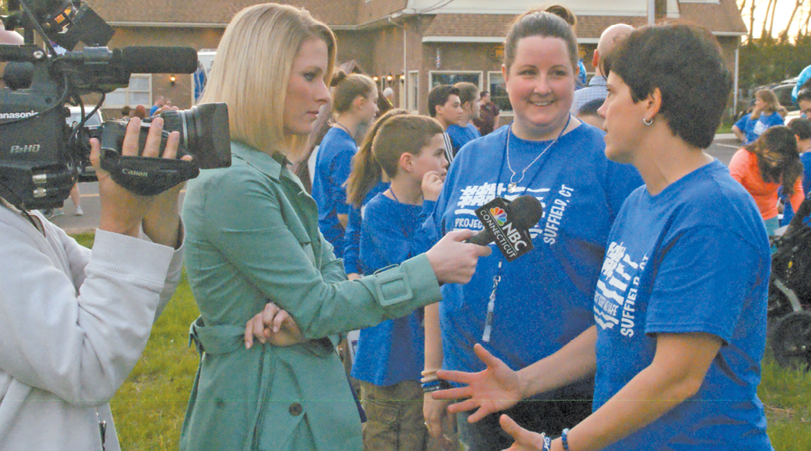 Tara Joyce of WVIT interviews Jill Caron, center, and Sue Davis during their Light-It-Up-Blue-Suffield party on the South Green April 28. They’re making great strides in their program to improve autism awareness.