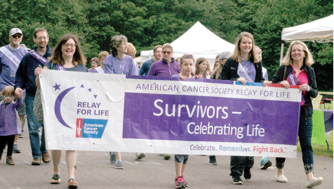Four survivors and caregivers carry the big banner in the first lap of this year’s Relay for Life. From the left: First selectman Melissa and Elizabeth Mack, Kelly and Dr. Carolyn Ray. When survivor Kelly Ray spoke after the noontime survivor’s lunch, she had changed to shorts, exposing her above-the-knee prosthetic left leg – the result of her osteosarcoma.
