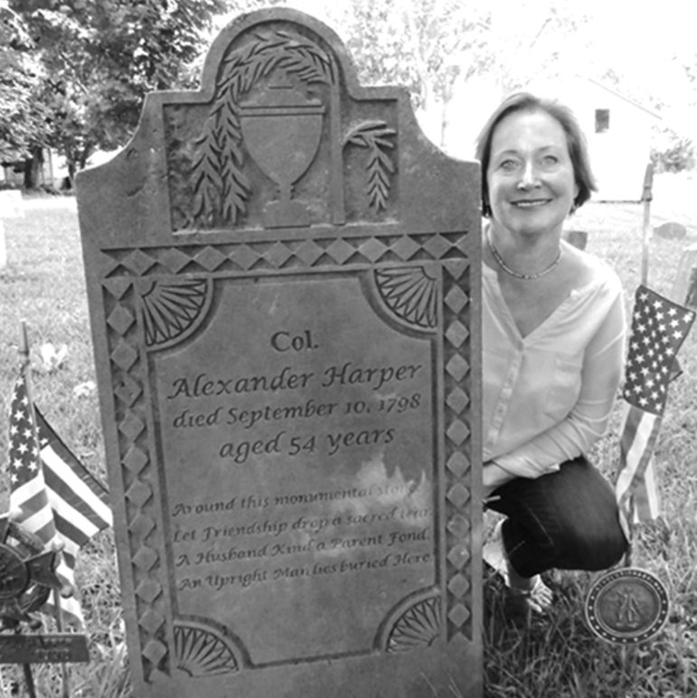 The author is pictured in 2015 next to the 1798 grave marker of her fifth great grandfather, Col. Alexander Harper, in the Alexander Harper Memorial Cemetery, Harpersfield, Ohio.