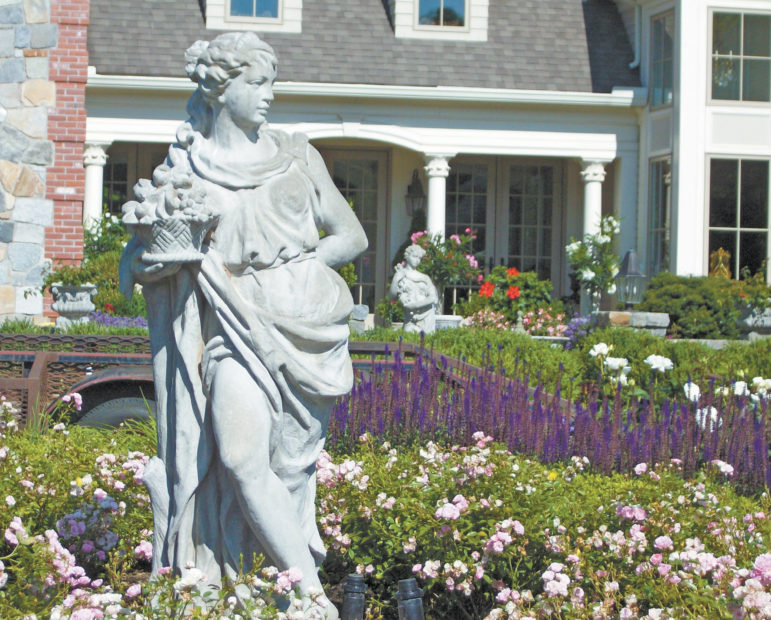 The statuary in this front door garden is surrounded by pink Fairy shrub roses and purple salvia.