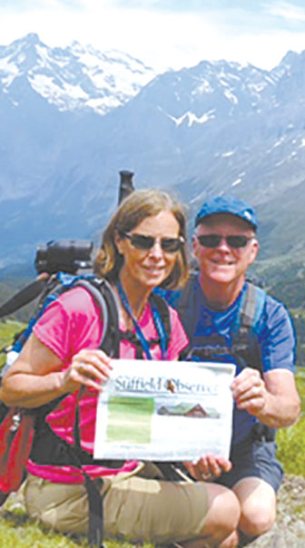 Hiking in the Berber Oberland Region of the Swiss Alps in June, Joan and Tom Heffernan enjoy a brief rest and a chance to read the current issue of the Observer. They report that the mountains in the background are the Schreckhorn and the Eiger.