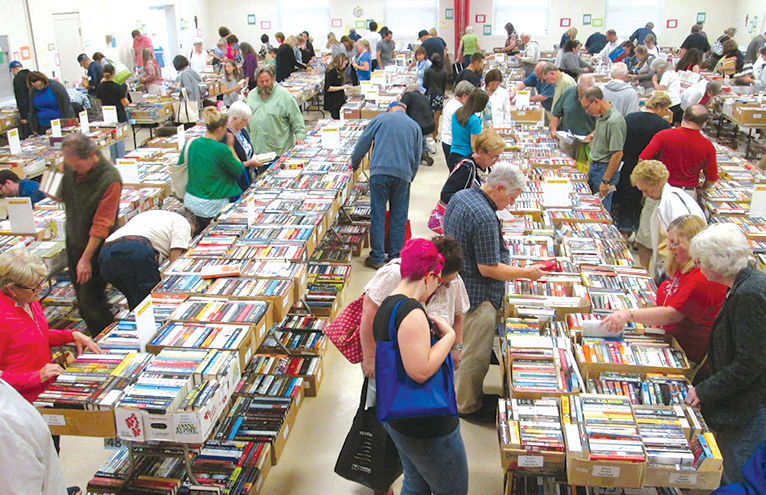 Dealers and adult bibliophiles crowd the tables at Friday evening’s paid preview of this year’s bigger-than-ever book sale offered by the Friends of the Library in Father Ted Hall.