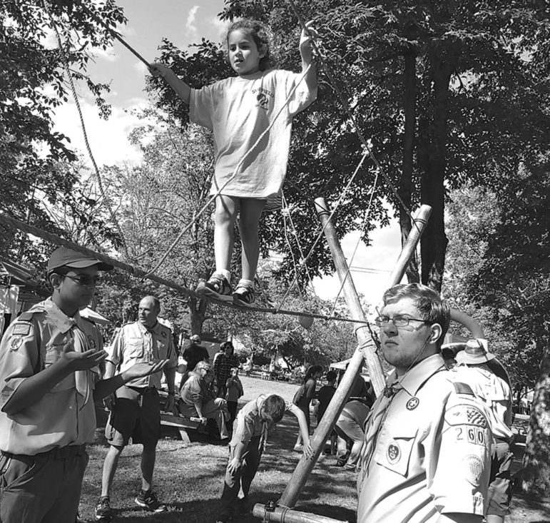 Six-year-old Elise Rodrigues looks very poised as she crosses Boy Scout Troop 260’s rope bridge, guarded by Scouts Jacob Quinn, left, and Sky Therian.