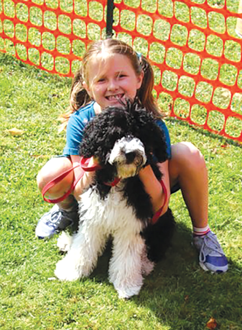 Amelia Shanks is all smiles as she poses with her dog, Piper, a Portuguese Water Dog.