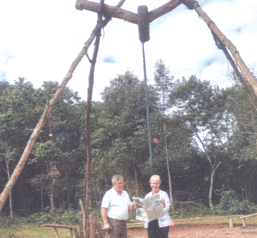 Tom and Carol Kaput are pictured with the Observer when they visited Akhta village in Laos this summer. The big pole frame, renewed every year in a happy festival, is used to swing as high as possible asking ancestral spirits for a rich harvest.