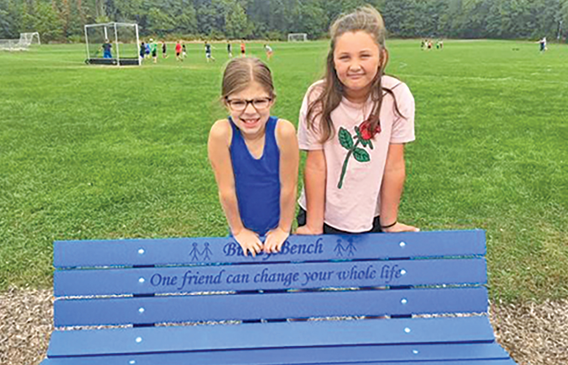 Happy with the new buddy bench at the McAlister playscape are from the left Jordan Rypysc and Alanna Dolan.  Lettered on the bench is: “One friend can change your whole life.”