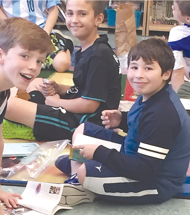 Friends enjoy newly purchased books from the annual fourth grade UNICEF book sale.