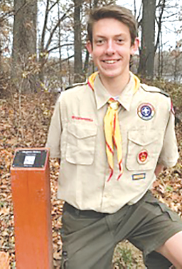 Eagle Scout Michael Sattan is pictured with one of the tree identification stations he designed and installed at Hilltop Farm.  The QR Code on a post near selected trees provides useful information about each tree. 
