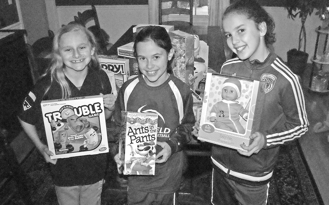 Hostess Colby Evans, left, is pictured with two of the team-mates who gathered at her home on December 17 with toys for kids in need.With her are Rylie Barile, center, and Breleigh Cooke. All three are sixth graders.