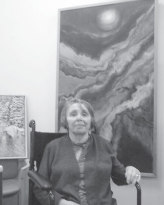 Roseann Mark is pictured with two of her abstract paintings among the several works she included in the activity room exhibition.