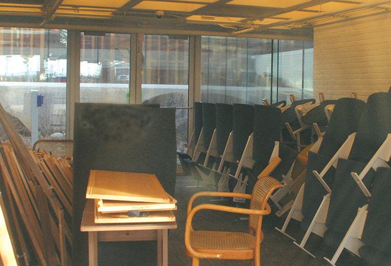 Viewed through a west window, auditorium seats are seen stacked in the lower lobby of the Kent Memorial Library. They were removed by the Sufffield Highway Crew, as the auditorium must be reconfigured to meet handicapped accessiblity and safe egress requirements before the room can be returned to use. Specific plans for a new seating installation are being considered.