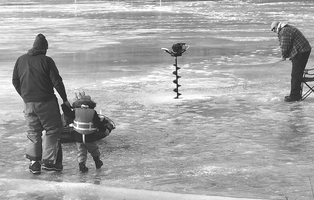 Preparing for ice fishing at Sunrise Park on a sunny January morning, Rick Trowbridge and his daughter Quinn venture across the ice to join grandpa Mertin Trowbridge