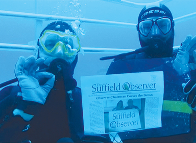 The Observer seems to be more durable than we expected, for here it is, taken along by Alan and Rob Fahrenholz while cage diving for great white sharks off Neptune Island in Southern Australia.  Or maybe they’re holding the corners of a big plastic sleeve with the paper inside. 